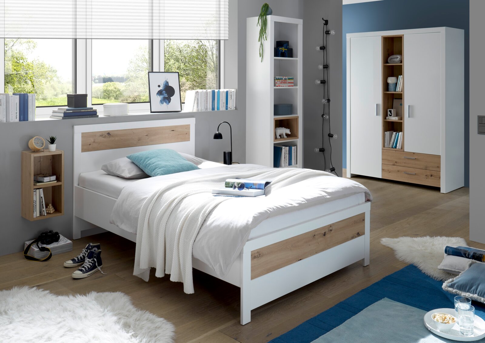 Modernes Schlafzimmer mit Standregal, Bett und Kleiderschrank in Holz- und Weißtönen, seitliche Perspektive