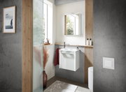 Modernes Gästebad mit weißem Waschbeckenunterschrank, Spiegel und minimalistischer Dekoration, seitliche Perspektive.
