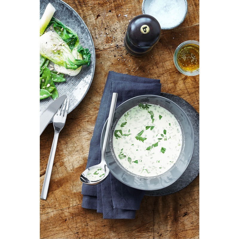 Saucenlöffel Nuova auf einem Holztisch neben einer Schüssel mit Kräutersauce, von oben betrachtet.