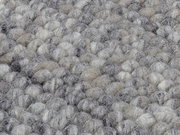 Nahaufnahme eines handgewebten Teppichs mit einer texturierten, grauen und beigen Oberfläche.