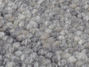 Nahaufnahme eines handgewebten Teppichs mit einer texturierten, grauen und beigen Oberfläche.