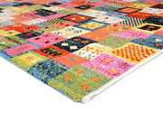 Bunter Designer Teppich mit Patchwork-Muster, perspektivisch von der Seite fotografiert.