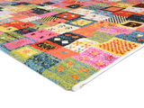 Bunter Designer Teppich mit Patchwork-Muster, perspektivisch von der Seite fotografiert.
