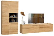Moderne Wohnwand in heller Holzoptik mit hoher Vitrine, Glasfach und breitem TV-Lowboard, dekoriert und aus frontaler Perspektive leicht von rechts gezeigt