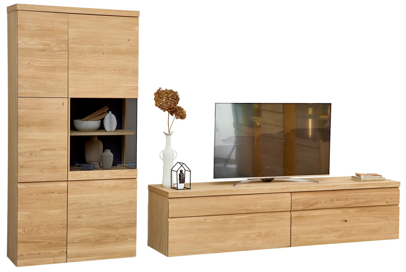 Moderne Wohnwand in heller Holzoptik mit hoher Vitrine, Glasfach und breitem TV-Lowboard, dekoriert und aus frontaler Perspektive leicht von rechts gezeigt