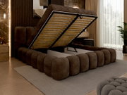 Een gestoffeerd bedframe in een moderne slaapkamer, gezien vanaf de zijkant, met een opklapbaar matras en opbergruimte eronder.