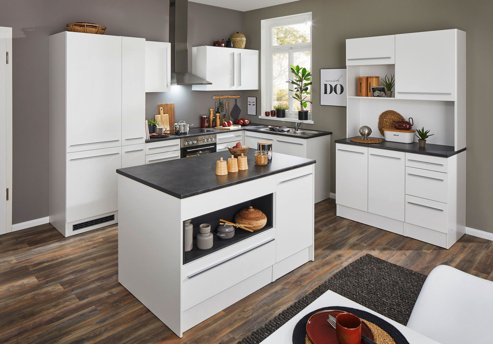 Yourkitchen Apothekerschrank JAZZ Moderne weiße Küche mit Kochinsel, Schränken und Geräten, aus der Perspektive eines offenen Raumes betrachtet.