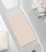 Beige Wanneneinlage Mirasol in einer Badewanne, von oben fotografiert, mit Handtüchern und Pflegeprodukten am Rand.