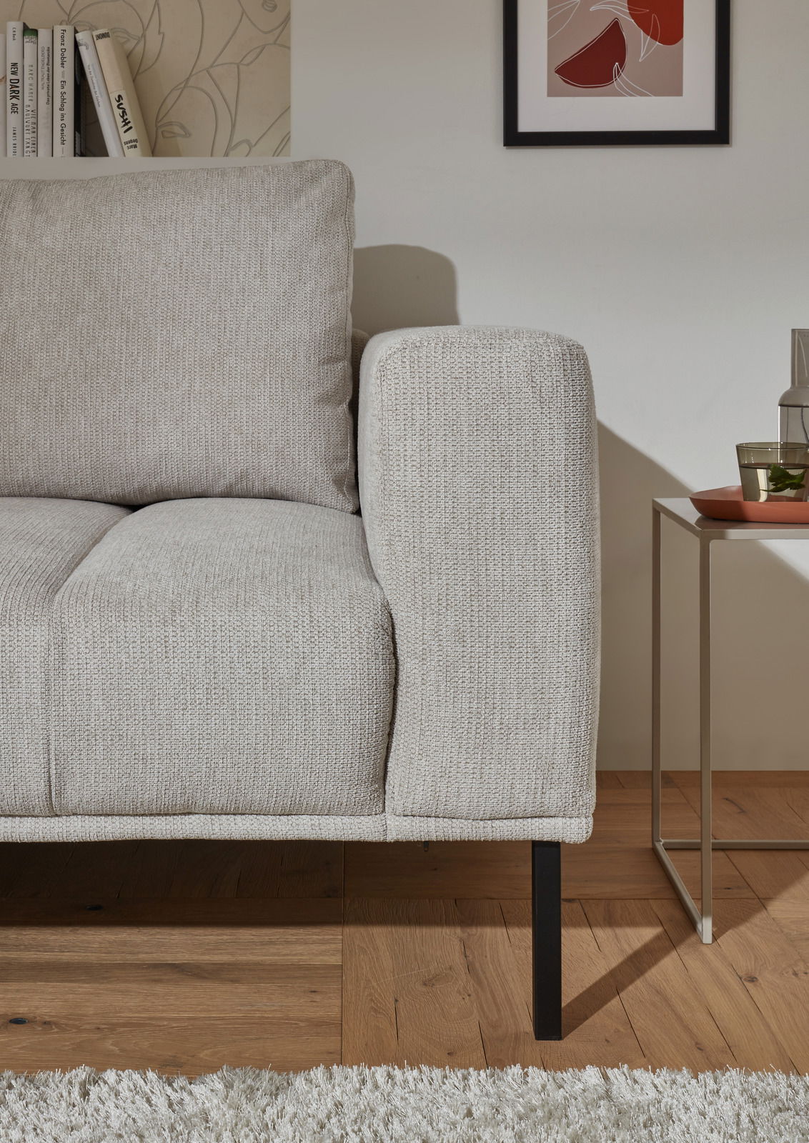 Nahaufnahme einer hellgrauen Eckgarnitur mit Armlehne und Kissen, seitliche Perspektive