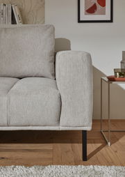 Nahaufnahme einer hellgrauen Eckgarnitur mit Armlehne und Kissen, seitliche Perspektive