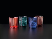 Vier bunte, geriffelte Becher aus Glas in Rot, Grün, Blau und Rosa auf schwarzem Hintergrund, seitliche Perspektive.