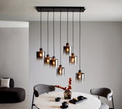Moderne Hängeleuchte mit mehreren Glaskörpern, die von der Decke hängen, in einem stilvoll eingerichteten Esszimmer. Perspektive von schräg unten.