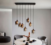 Moderne Hängeleuchte mit mehreren Glaskörpern, die von der Decke hängen, in einem stilvoll eingerichteten Esszimmer. Perspektive von schräg unten.