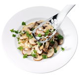 Servierlöffel Nuova 25cm aus Edelstahl, von oben fotografiert, über einem Teller mit Pilzen und Petersilie.