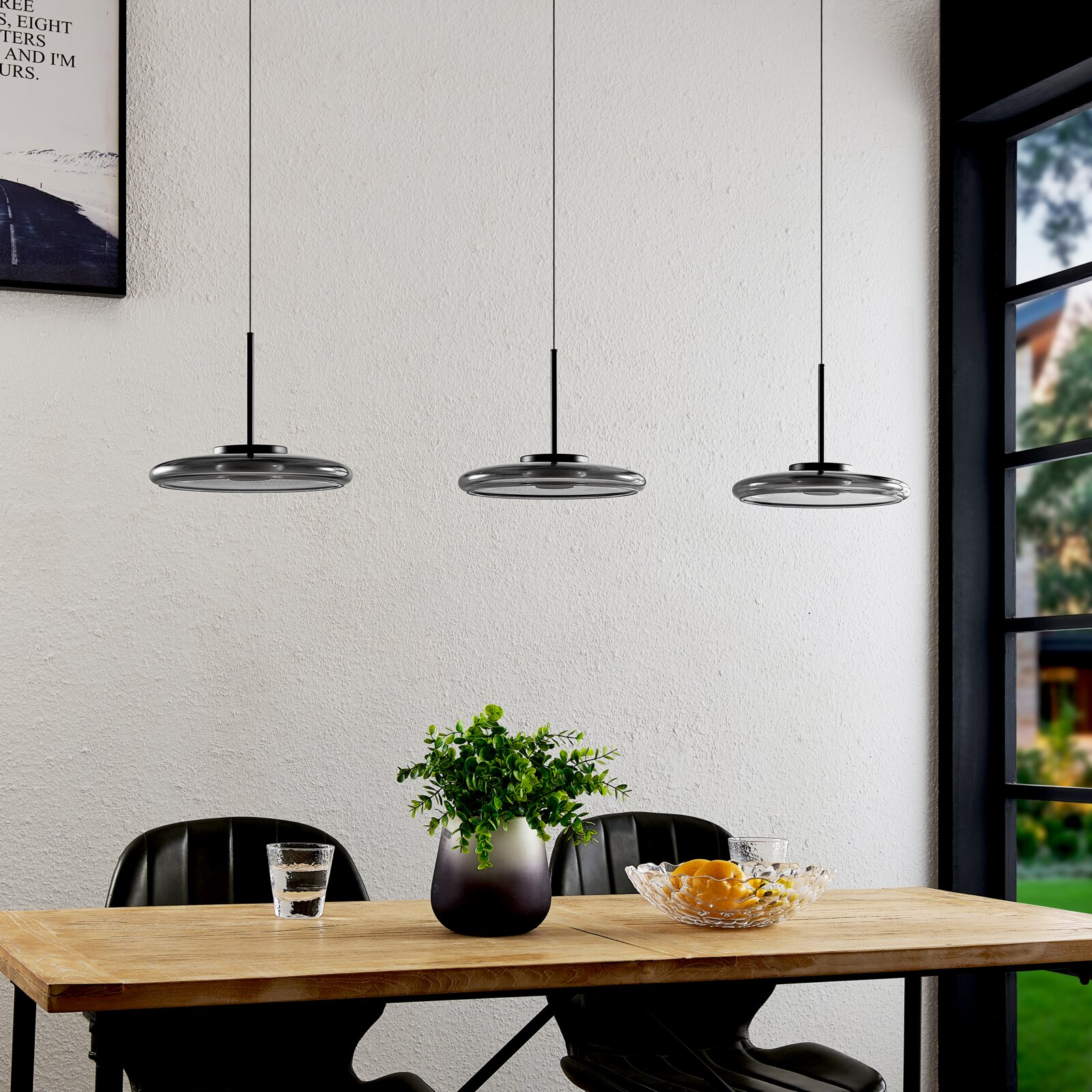 Moderne LED-Hängeleuchte in dreifacher Ausführung über einem Esstisch, seitliche Perspektive.