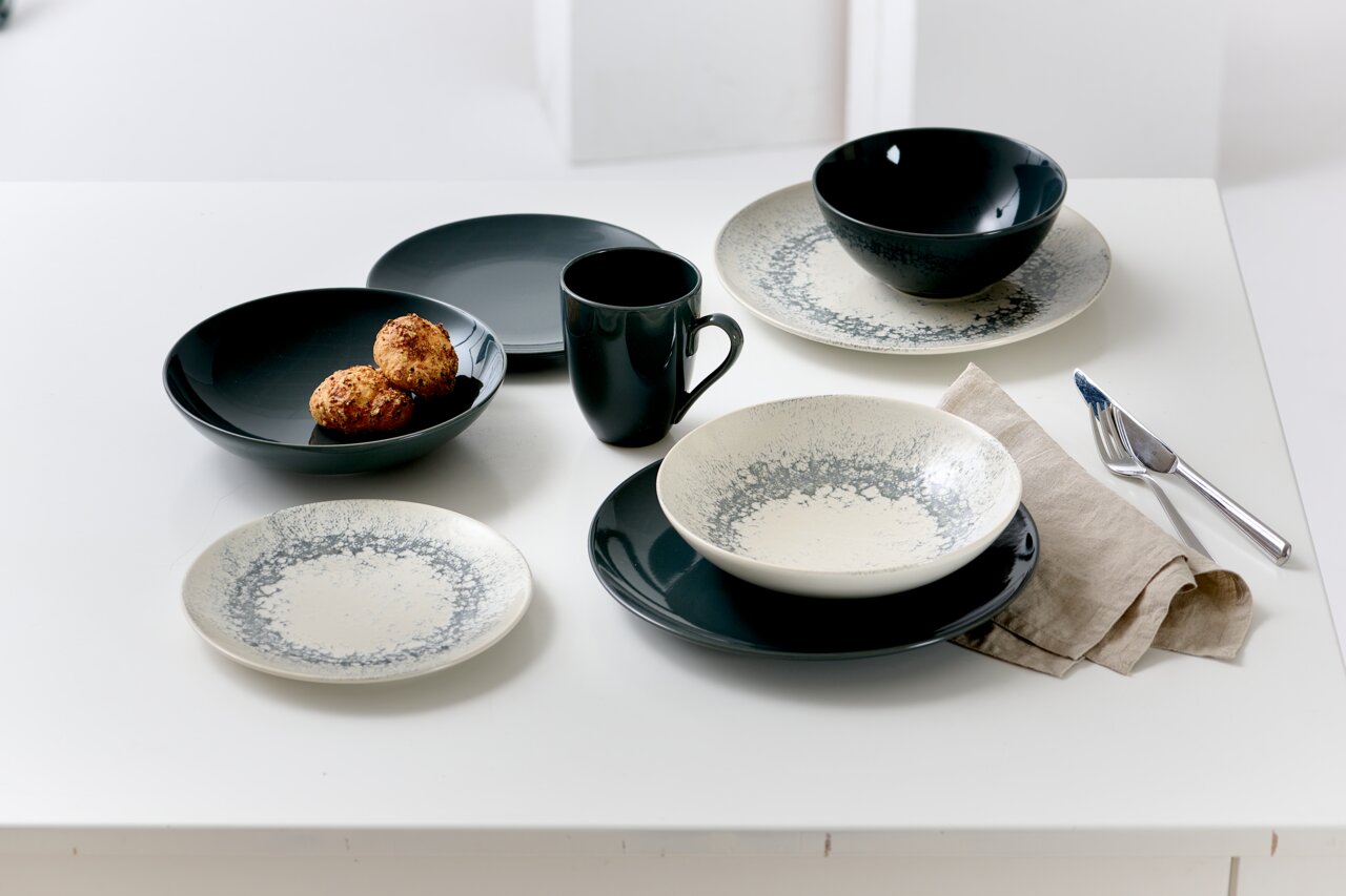 Ritzenhoff & Breker Tafelservice 18-tlg. CECINA Tafelservice Cecina Graphit 18-teilig, bestehend aus Tellern, Schalen und Tassen in einem modernen Design mit grauen und weißen Akzenten, auf einem Tisch von oben fotografiert.