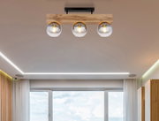 Moderne Deckenleuchte mit drei Glaskugeln und Holzhalterung, von unten betrachtet.