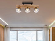 Moderne Deckenleuchte mit drei Glaskugeln und Holzhalterung, von unten betrachtet.