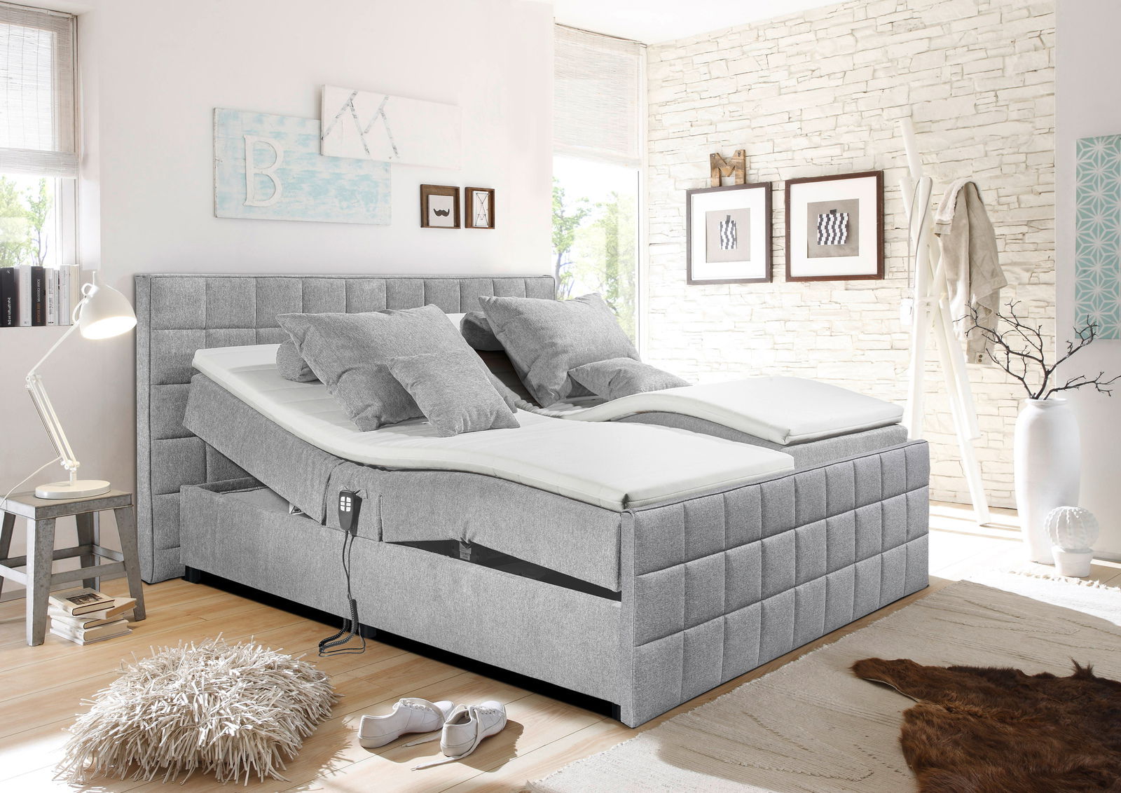 Graues Polsterbett mit verstellbaren Matratzen, seitliche Perspektive, in modernem Schlafzimmer mit heller Dekoration.