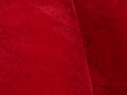 Nahaufnahme eines roten, weichen Fellteppichs mit flauschiger Textur.