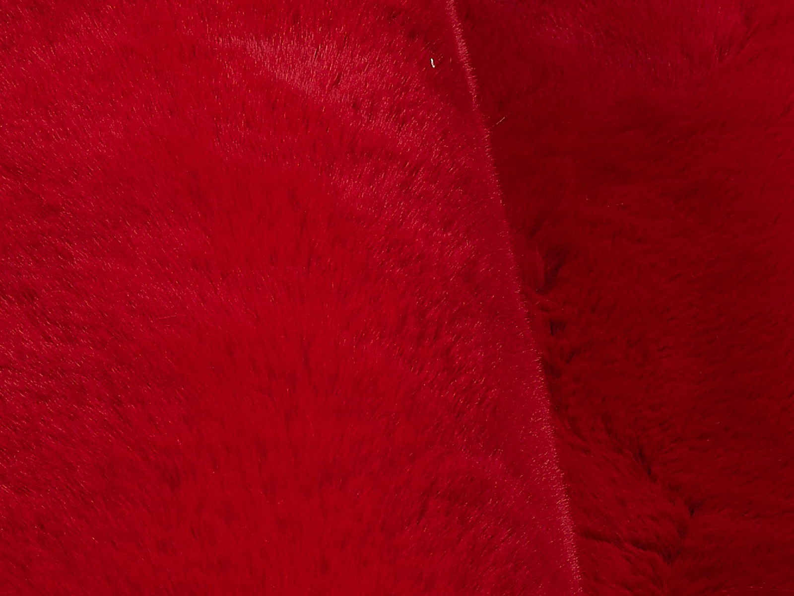 Nahaufnahme eines roten, weichen Fellteppichs mit flauschiger Textur.