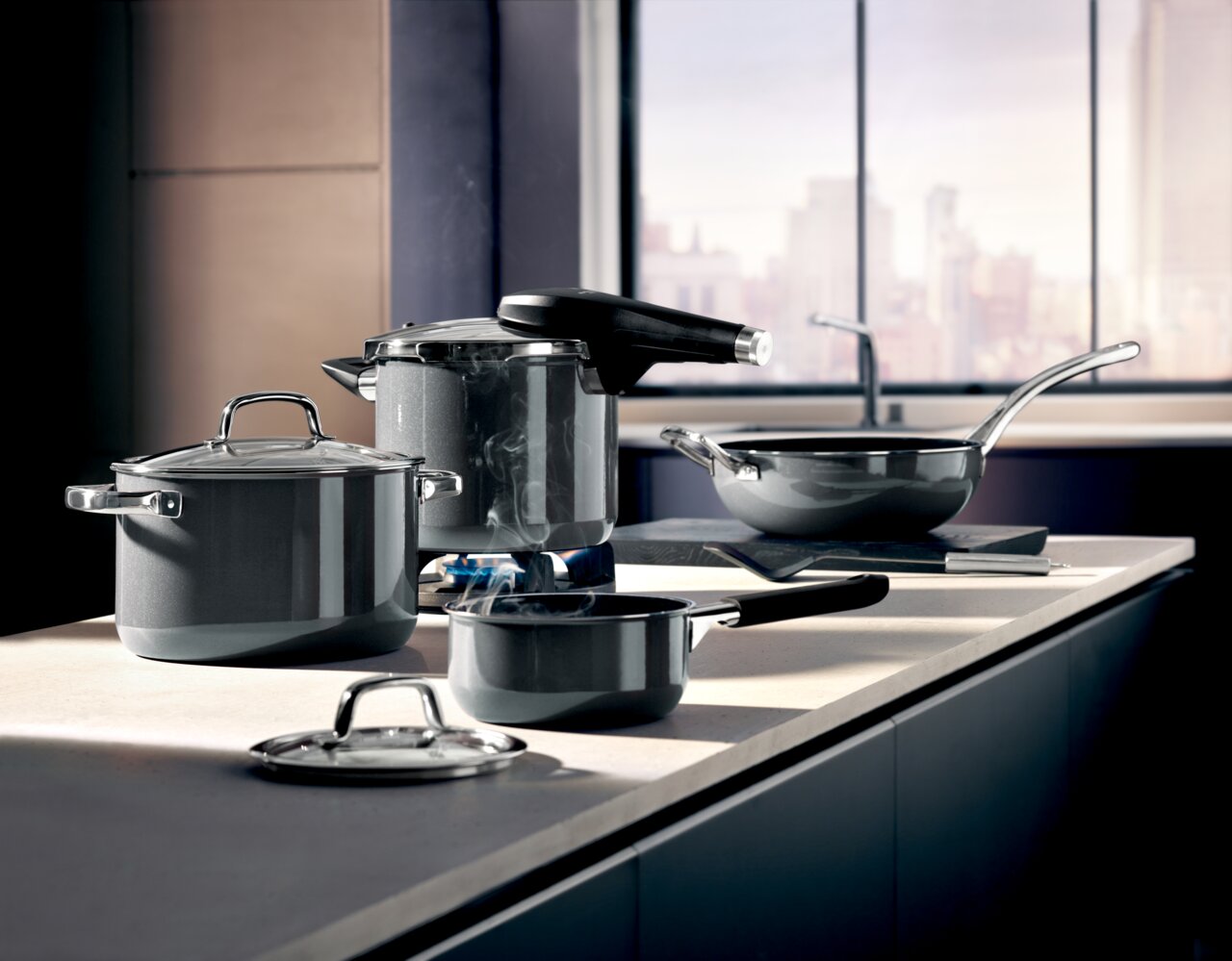 Moderne Küche mit einem Schnellkochtopf Fusiontec Perf und weiteren Töpfen und Pfannen auf einer Arbeitsplatte, seitliche Perspektive.