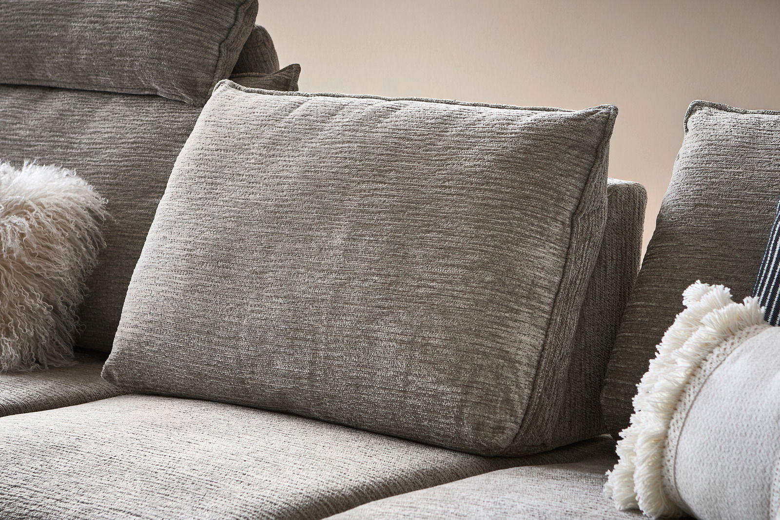 Nahaufnahme eines grauen Sofas mit strukturierten Kissen und dekorativen Kissen, seitliche Perspektive.