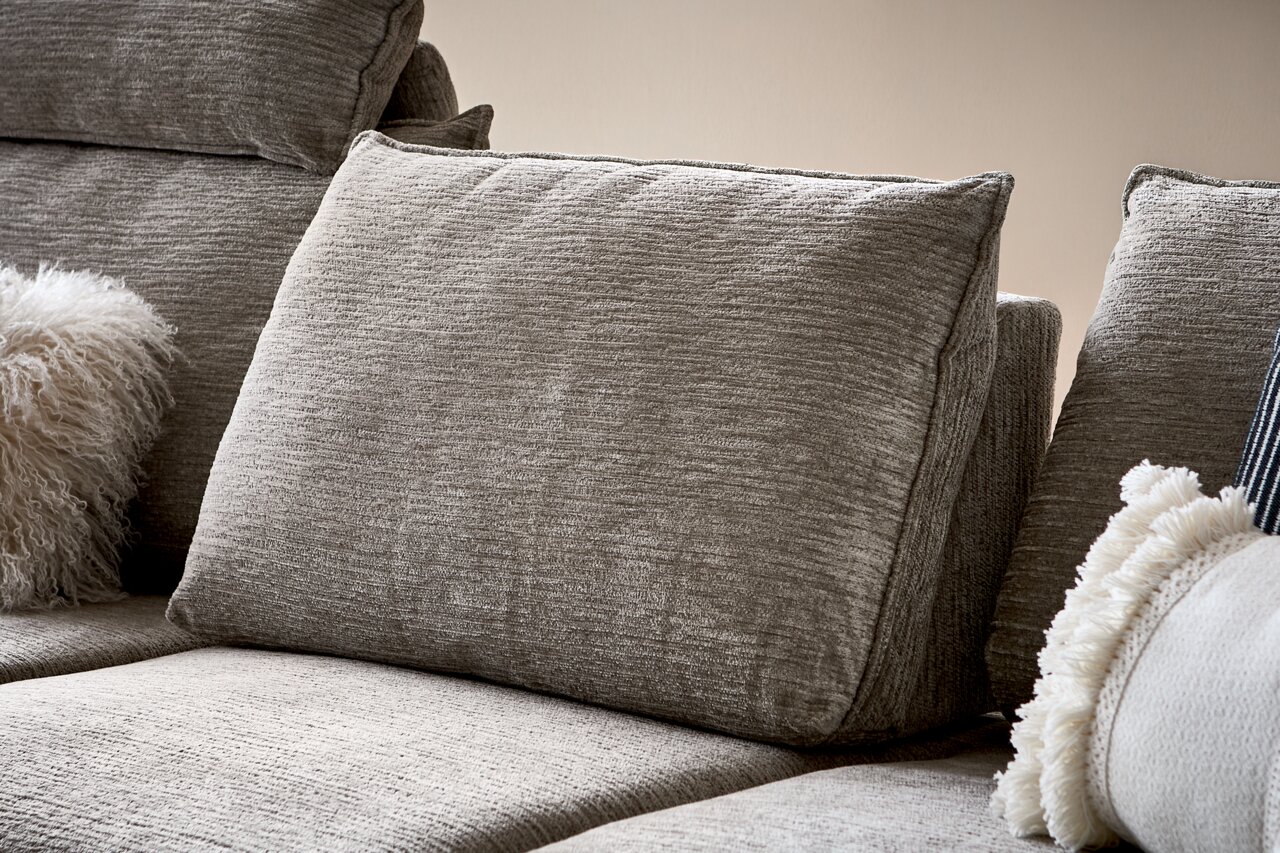 Nahaufnahme eines grauen Sofas mit strukturierten Kissen und dekorativen Kissen, seitliche Perspektive.