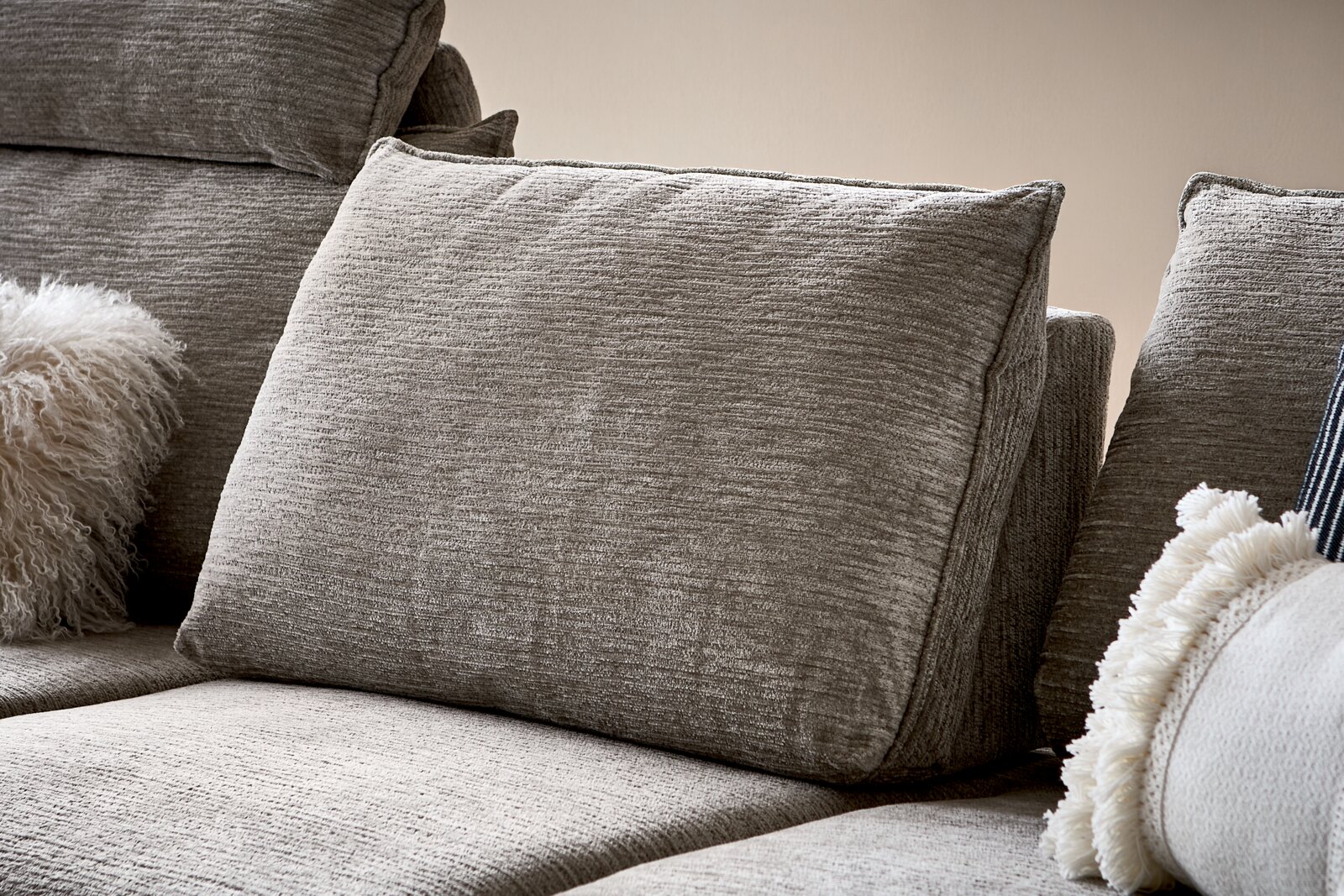 Nahaufnahme eines grauen Sofas mit strukturierten Kissen und dekorativen Kissen, seitliche Perspektive.