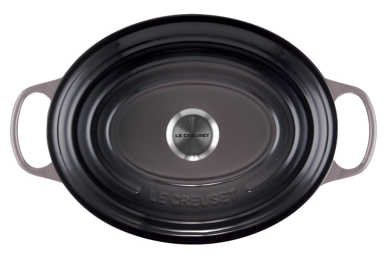 Ovaler Bräter von oben mit zwei Griffen, dunkle Farbe, Markenname Le Creuset auf dem Deckelknauf.