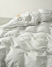 Bettwäsche in hellem Beige auf einem Bett, aus der Perspektive von der Seite fotografiert.