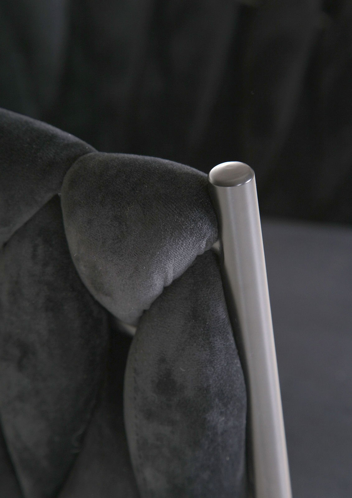 Nahaufnahme eines Sessels mit schwarzem, gepolstertem Stoff und einem silbernen Metallrahmen.