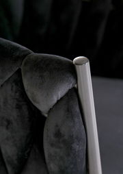 Nahaufnahme eines Sessels mit schwarzem, gepolstertem Stoff und einem silbernen Metallrahmen.