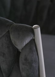 Nahaufnahme eines Sessels mit schwarzem, gepolstertem Stoff und einem silbernen Metallrahmen.