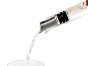 Nahaufnahme eines Ausgießers und Verschlusses, der Flüssigkeit in ein Glas gießt, seitliche Perspektive