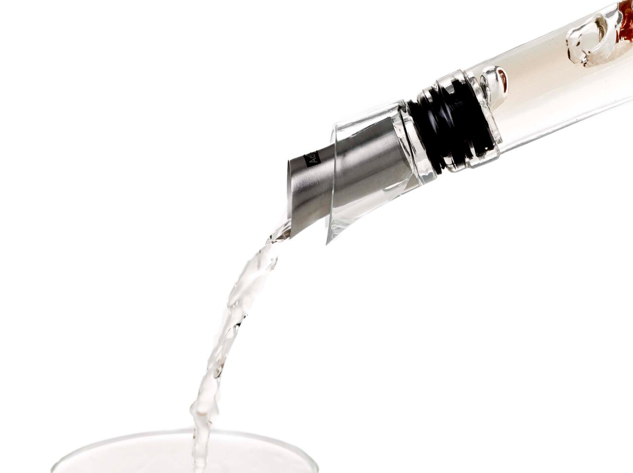 Nahaufnahme eines Ausgießers und Verschlusses, der Flüssigkeit in ein Glas gießt, seitliche Perspektive