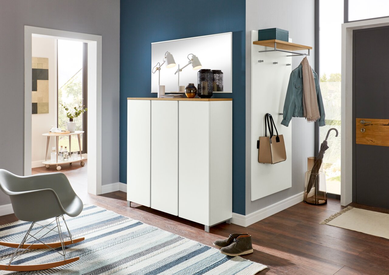 Moderner Eingangsbereich mit weißem Schuhschrank, Spiegel und Garderobenpaneel. Perspektive von vorne.
