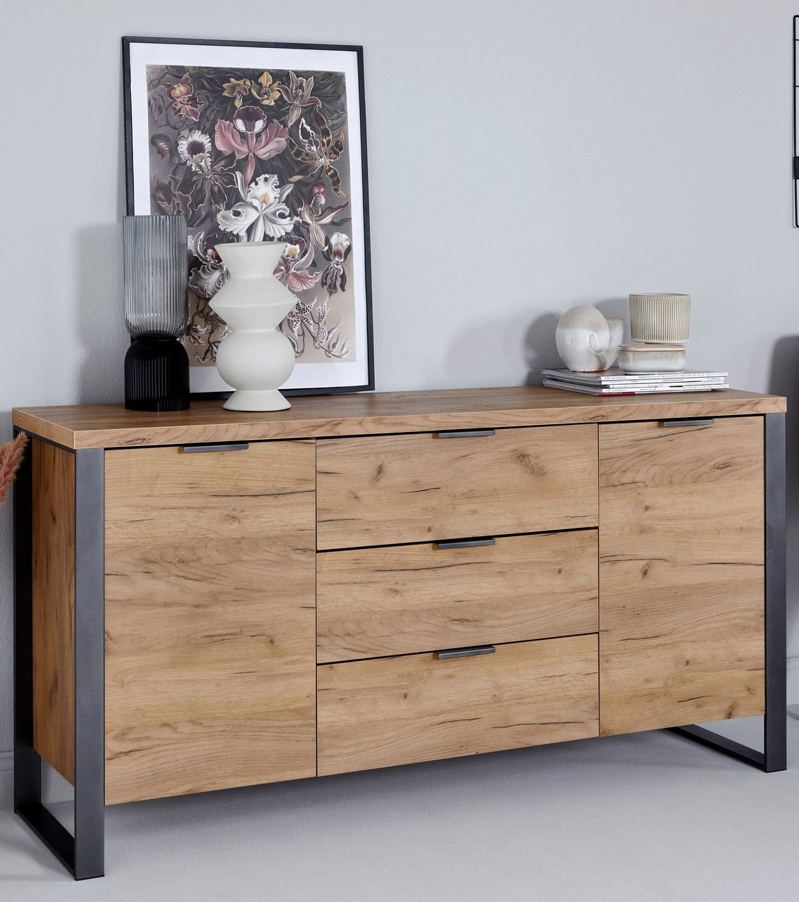 Sideboard aus Holz mit drei Schubladen und zwei Türen, dekoriert mit Vasen und einem Bild, seitliche Perspektive