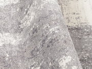 Nahaufnahme eines Designer Teppichs in Grau- und Weißtönen mit strukturierter Oberfläche, seitliche Perspektive