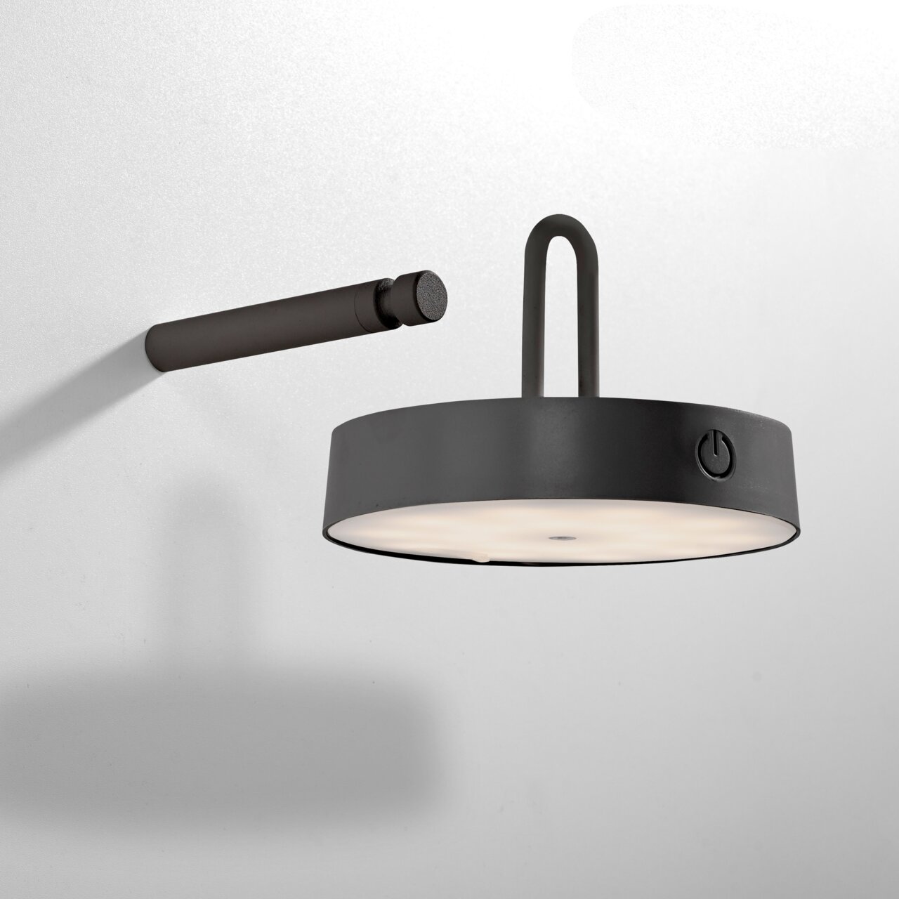 Moderne wandlamp ARMA in zijaanzicht met een ronde, zwarte behuizing en een ingebouwde schakelaar.