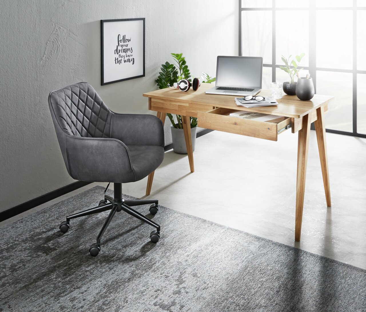 Moderner Schreibtisch aus Holz mit Schublade, Laptop und Dekorationen, seitliche Perspektive