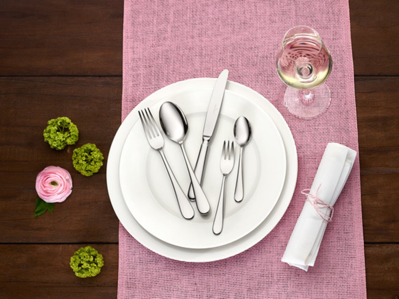 Villeroy & Boch Tafelbesteck 30tlg. OSCAR Elegantes Tafelbesteck-Set Oscar, 30-teilig, auf einem gedeckten Tisch mit rosa Tischläufer, Blumen und einem Glas Weißwein, aus der Vogelperspektive.