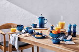Frühstückstisch mit blauen Bechern und Geschirr in Azure-Farbe, von oben betrachtet.