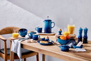 Frühstückstisch mit blauen Bechern und Geschirr in Azure-Farbe, von oben betrachtet.