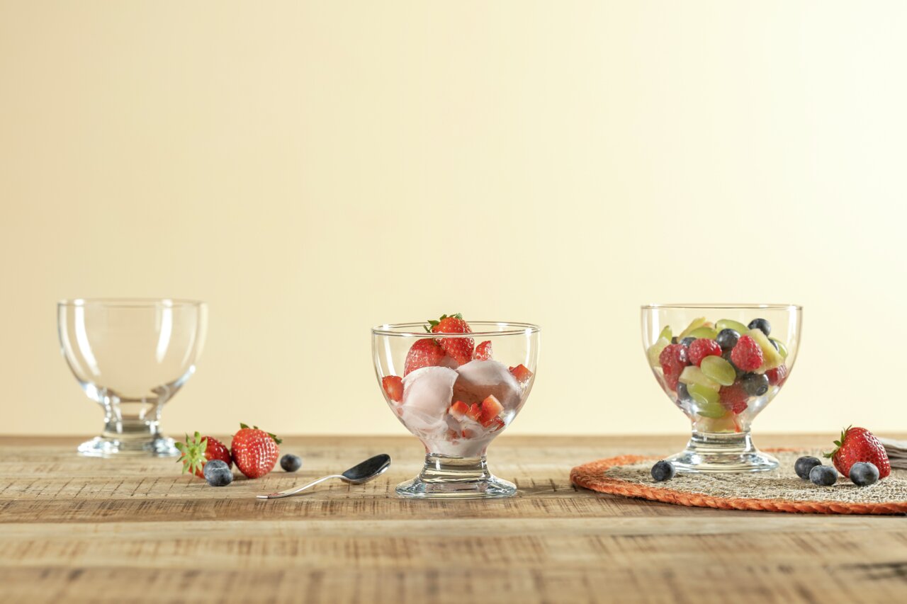 Leonardo Dessertschale JOE MONTANA Drei Dessertschalen aus Glas, gefüllt mit frischen Früchten und Eis, auf einem Holztisch. Perspektive von vorne.