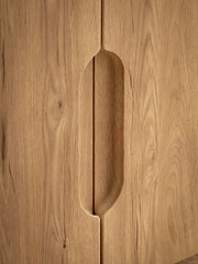Nahaufnahme einer Holzschrankfront mit eingefrästem, vertikalem Griffdetail in der Mitte, Frontansicht