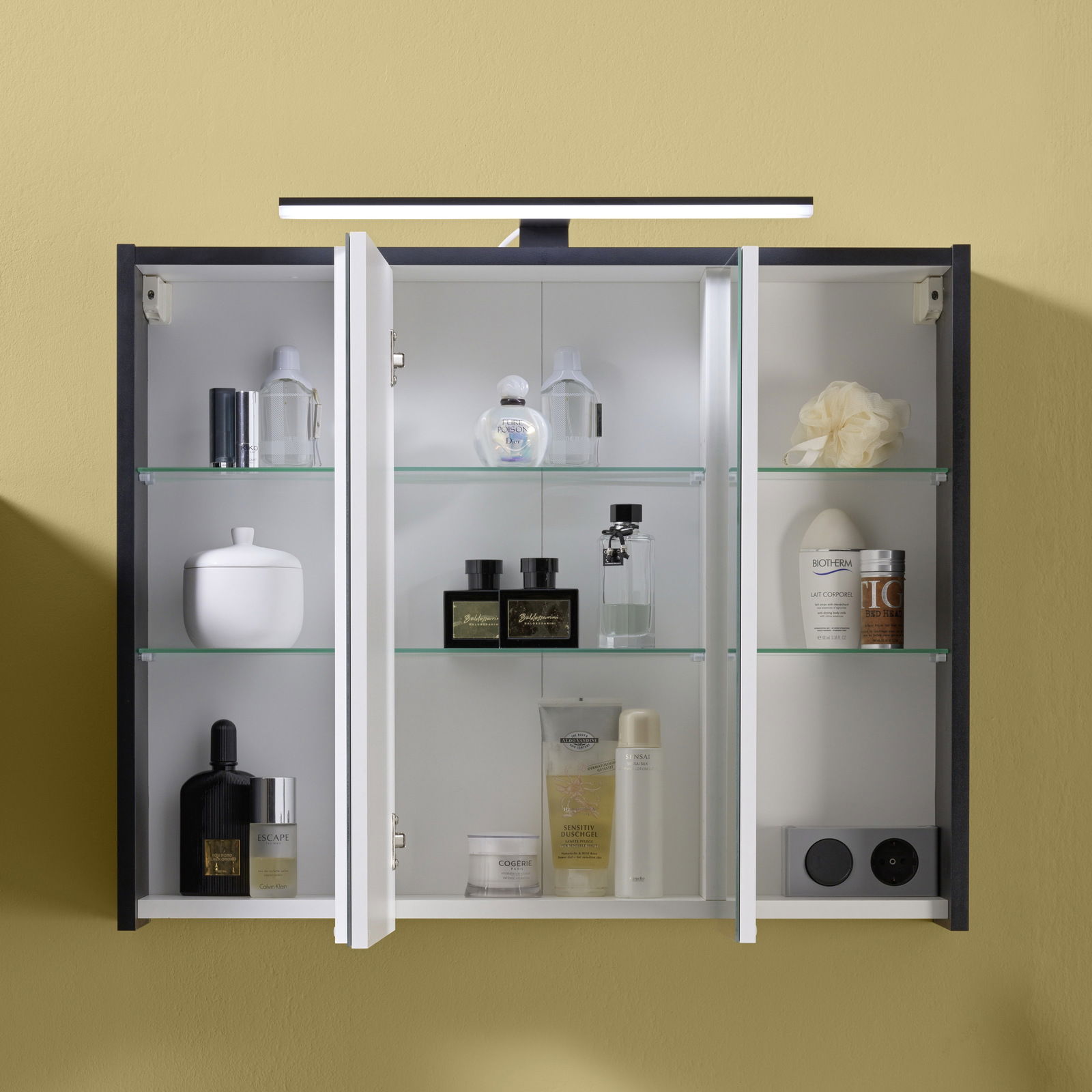 Spiegelschrank mit geöffneten Türen, gefüllt mit verschiedenen Pflegeprodukten, aus frontaler Perspektive fotografiert.