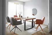 Moderner Esstisch aus Holz mit Metallbeinen, umgeben von stilvollen Stühlen in einem hellen Raum mit großem Fenster, aus seitlicher Perspektive fotografiert.