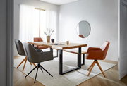 Moderner Esstisch aus Holz mit Metallbeinen, umgeben von stilvollen Stühlen in einem hellen Raum mit großem Fenster, aus seitlicher Perspektive fotografiert.