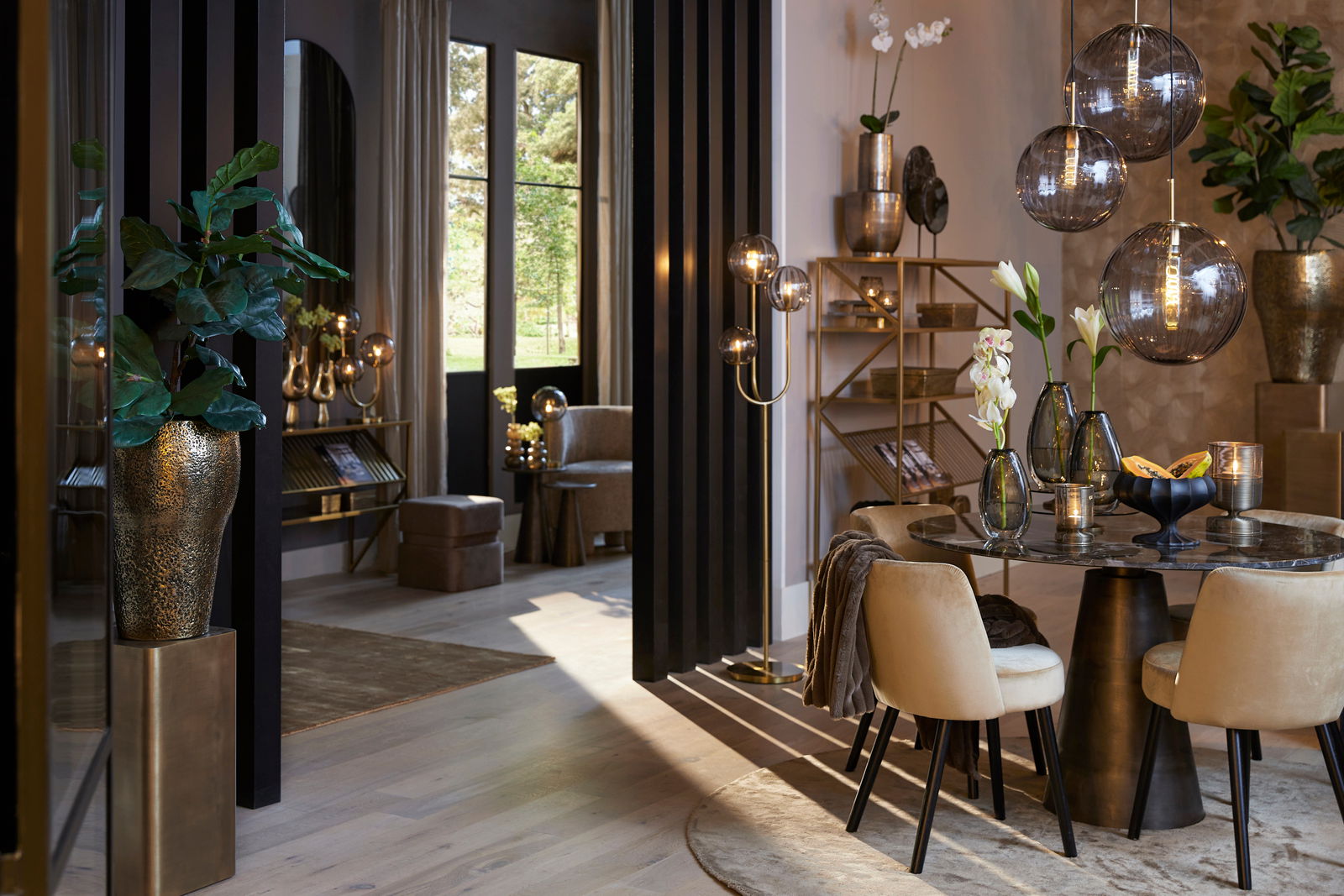 Elegantes Wohnzimmer mit modernen Möbeln und Dekorationen, darunter eine goldene Säule mit einer Pflanze darauf, im Vordergrund links.